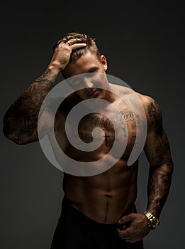 Muscular man with tattooes in deep shadows