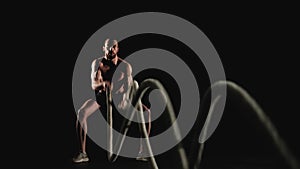 Muscular man training with battle ropes