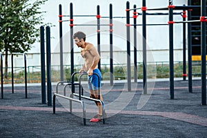 Muscular man warming up before exercise at crossfit ground doing push ups as part of training. Sport concept