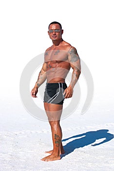 Muscular man on white background with sand