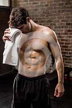 Muscular man wiping his face with towel