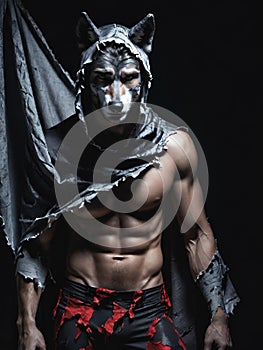 muscular man in wolf mask posing against dark background