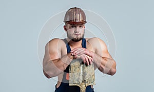 muscular man worker in engineer boilersuit and protective hard hat hold shovel, labor day