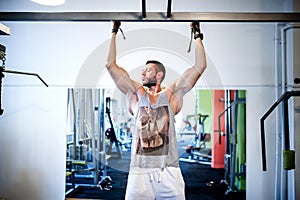 Muscular man working out at gym, chin ups