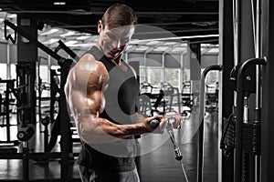 Muscular man working out in gym doing exercise for biceps, strong male bodybuilder