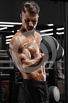 Muscular man working out in gym doing exercise for biceps, strong male bodybuilder