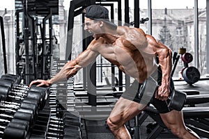 Muscular man working out in gym doing exercises for back. Single Arm Dumbbell Row