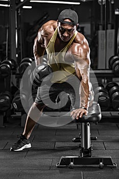 Muscular man working out in gym doing exercises for back. Single Arm Dumbbell Row