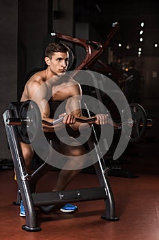 Muscular man working out in gym doing exercises with barbell