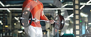 Muscular man working out in gym doing exercises with barbell at biceps