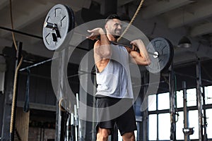 Muscular man working out in gym doing exercises with barbell at biceps