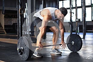 Muscular man working out in gym doing exercises with barbell at biceps