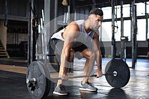 Muscular man working out in gym doing exercises with barbell at biceps