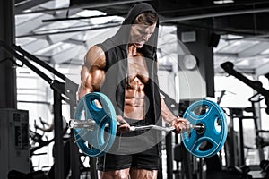 Muscular man working out in gym doing exercises with barbell for biceps, strong male naked torso abs