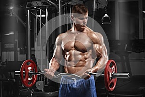 Muscular man working out in gym doing exercises with barbell at biceps, strong male naked torso abs