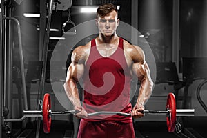 Muscular man working out in gym doing exercises with barbell, strong male