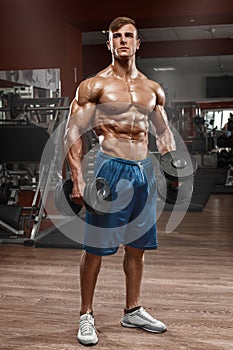 Muscular man working out in gym doing exercises with barbell, strong male naked torso abs