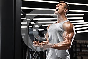 Muscular man working out in gym doing exercises for biceps, strong male