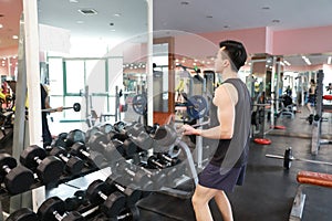 Muscular man working out in gym doing exercises with dumbbells at biceps, strong male naked torso abs