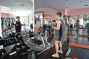 Muscular man working out in gym doing exercises with dumbbells at biceps, strong male naked torso abs