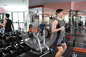 Muscular man working out in gym doing exercises with dumbbells at biceps, strong male naked torso abs