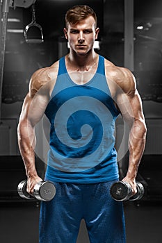 Muscular man working out in gym doing exercises with dumbbells, strong male torso