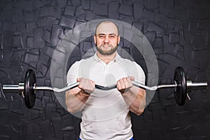 Muscular man working out in gym doing exercises, strong male with a barbell.