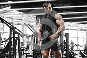 Muscular man working out in gym doing exercises, strong male bodybuilder