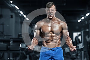 Muscular man working out in gym doing exercises, strong male torso abs