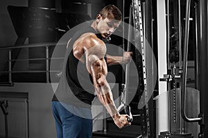 Muscular man working out in gym doing exercises at triceps, strong male photo