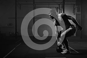 Muscular man working out with kettlebell in gym