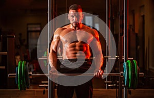 Muscular man workout with barbell at gym. Bodybuilder athletic man with six pack, perfect abs, shoulders, biceps