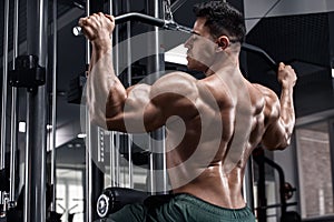 Muscular man workout in gym, doing exercise for back. Strong male rear view