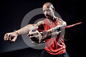 Muscular man during workout with suspension straps TRX on dark studio