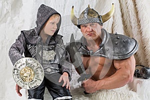 A muscular man with young son in costume viking