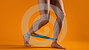 Muscular men`s legs with elastic band for fitness, do exercises to strain the leg muscles.