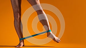 Muscular men& x27;s legs with elastic band for fitness, do exercises to strain the leg muscles.