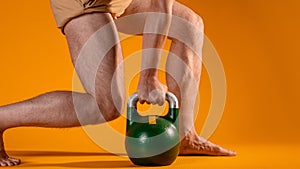 Muscular men`s legs in a squat and a kettlebell in the hands.