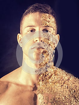 Muscular young man covered with golden specks