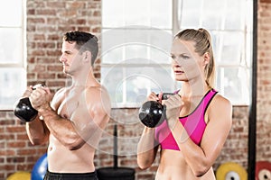 muscular serious couple with kettlebells