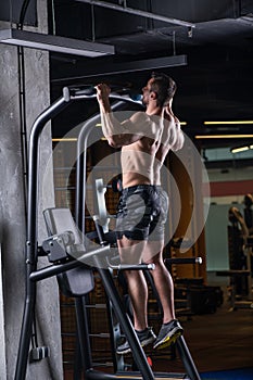 Muscular sexy young man doing exercise for the back on horizontal bar