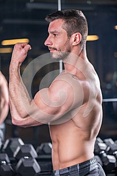 Muscular sexy young man posing with biceps contraction