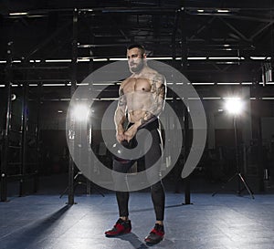 Muscular shirtless athlete doing kettlebell swings.Functional tr
