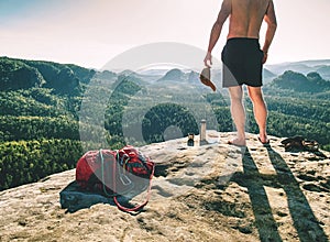 Muscular shirtless climber man with backpack on rock watch