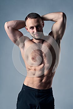 Muscular shirtless man posing with hands over head