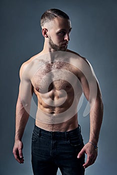 Muscular shirtless man standing with hands in pockets