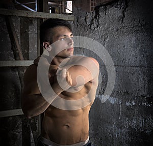 Muscular shirtless young man inside abandoned building