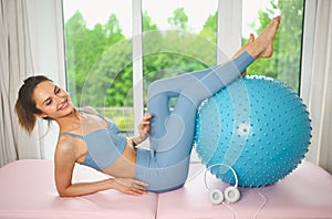 Muscular slim attractive female, flat belly perfect body. Beautiful fit woman doing yoga exercises with fitness pilates blue ball