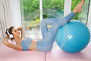 Muscular slim attractive female, flat belly perfect body. Beautiful fit woman doing yoga exercises with fitness pilates blue ball