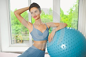 Muscular slim attractive female, flat belly perfect body. Beautiful fit woman doing yoga exercises with fitness pilates blue ball